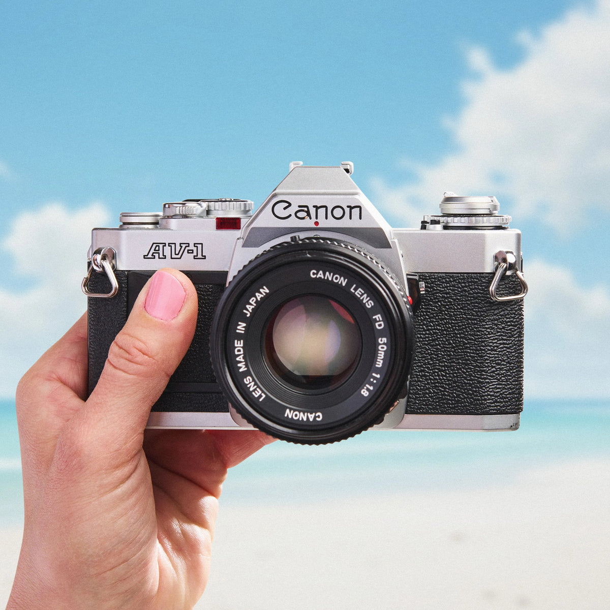 Canon AV-1 | 35mm Film Camera held in a hand with a blue sky background