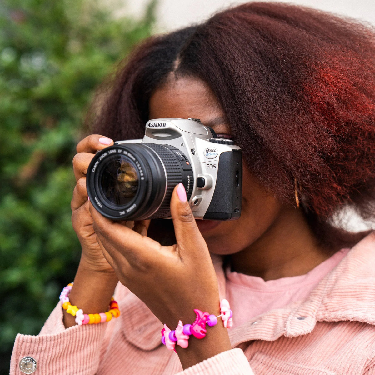 Person holding a Canon EOS Rebel 2000 film camera with a blurred green background