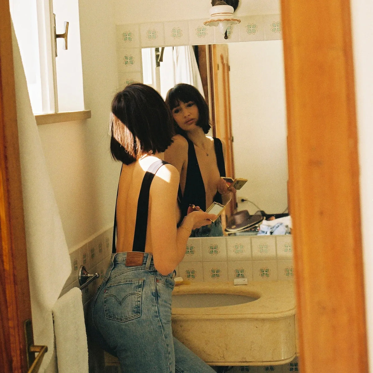 image of a Woman in a bathroom looking at herself in the mirror taken with a Canon FTB 35mm film camera  