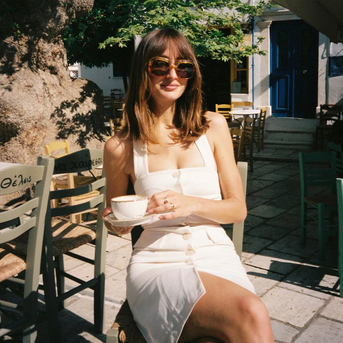 image of a Woman in a white dress holding a cup outdoors in a sunlit setting taken with a Canon FTB 35mm film camera  