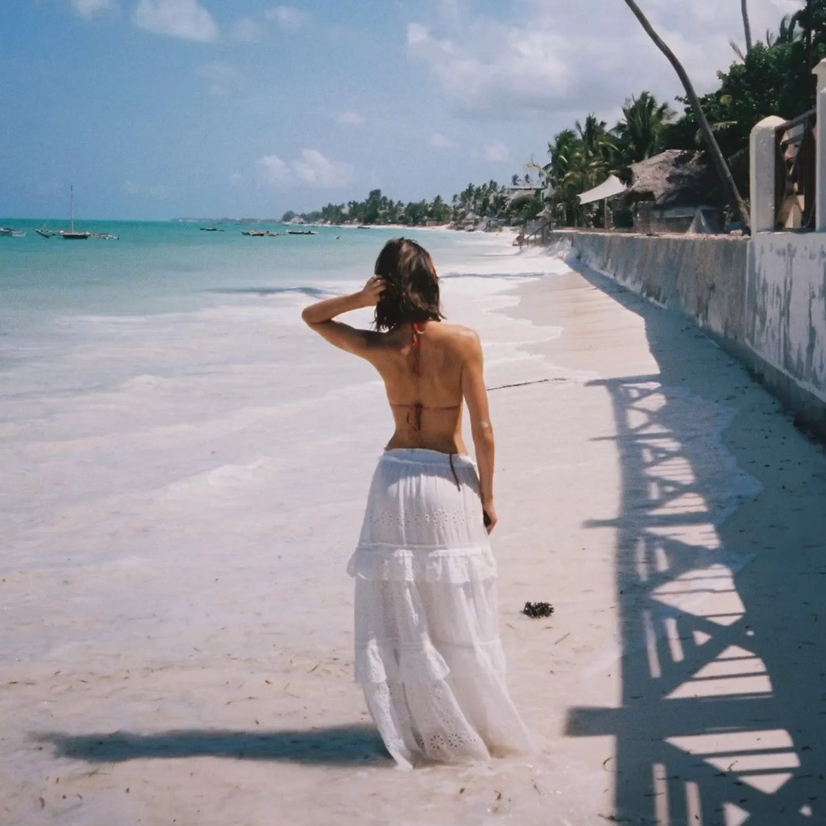 Woman in a white dress standing on a sandy path by the ocean with palm trees in the background taken with a Canon FTB 35mm film camera  
