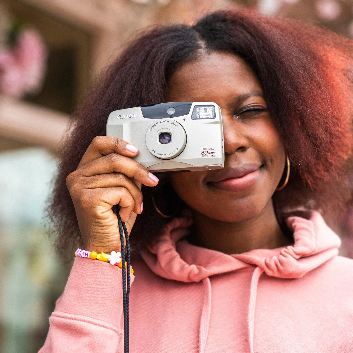 Person holding a Canon Sure Shot 60 Zoom 35mm Camera with a blurred background