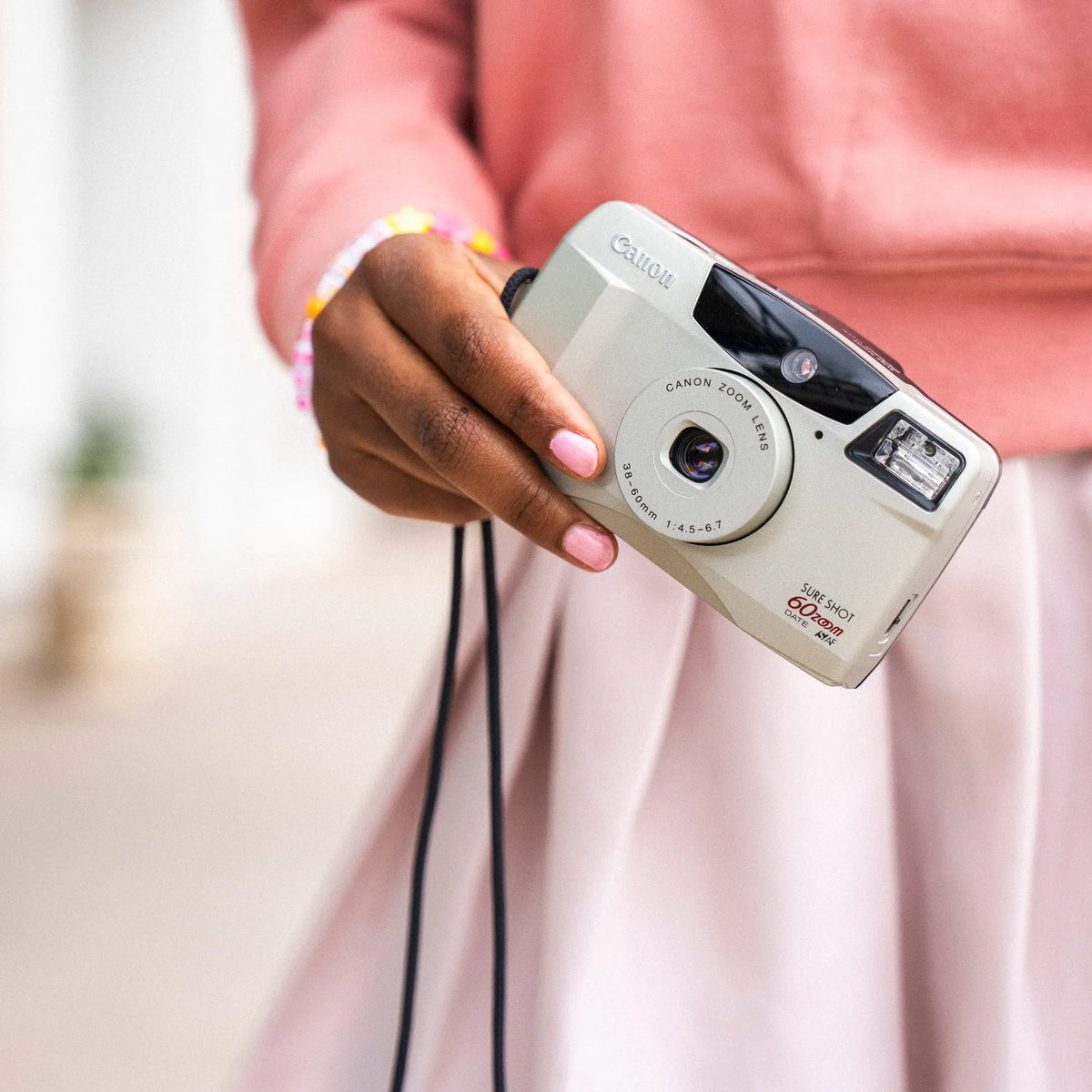 Person holding a Canon Sure Shot 60 Zoom 35mm Camera with a blurred background