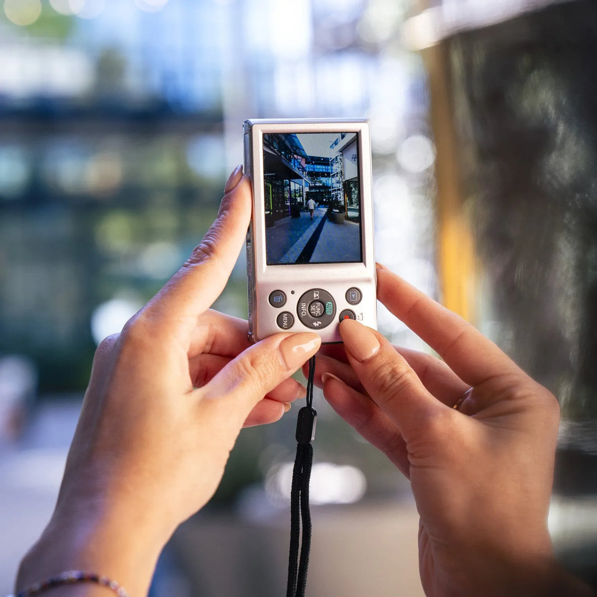 Person holding a Canon Powershot ELPH 135 camera with a blurred background