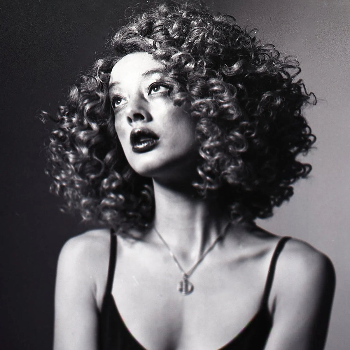 Black and white portrait of a woman with curly hair against a dark background taken with a Nikon F2 35mm Film Camera