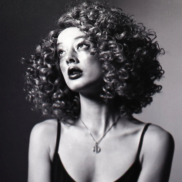 Black and white portrait of a woman with curly hair against a dark background taken with a Nikon F2 35mm Film Camera