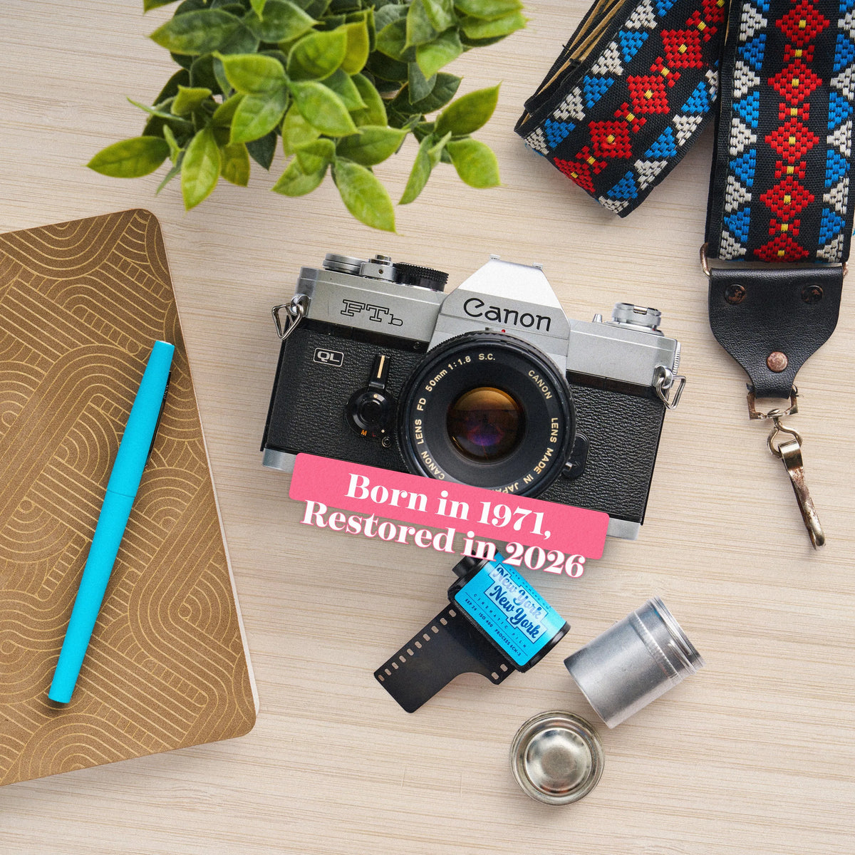 Canon FTB 35mm film camera  with film and accessories on a wooden surface