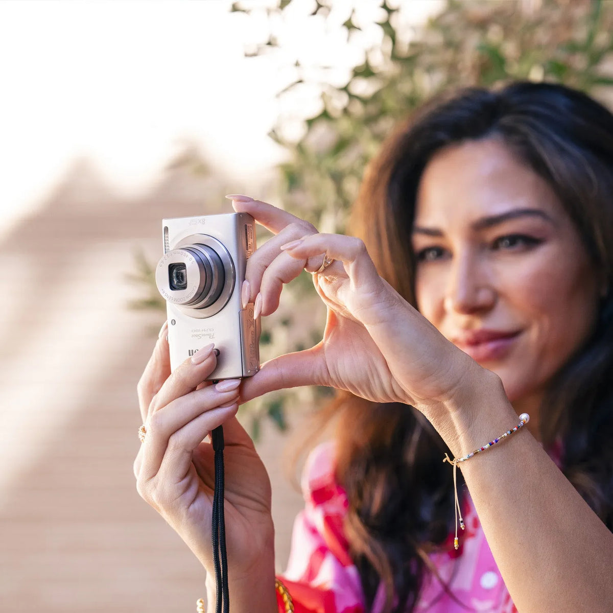 Woman taking a photo outdoors with a silver Canon PowerShot ELPH 180 digital camera