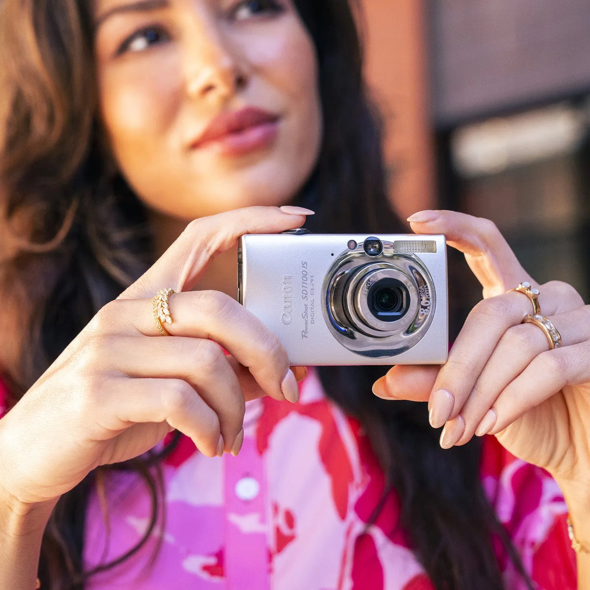 Woman holding a Canon PowerShot ELPH SD1100 IS with a blurred background