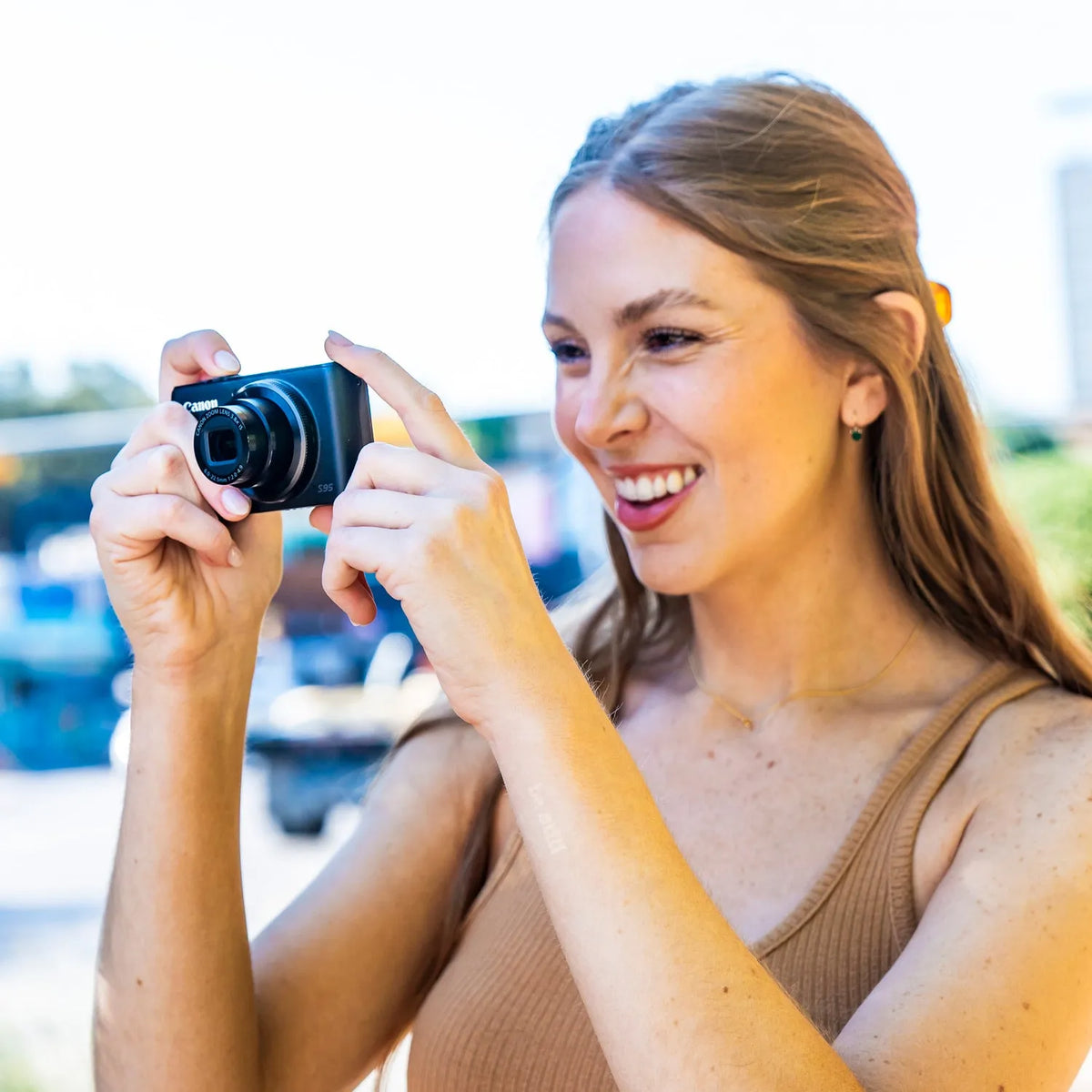 Woman taking a photo outdoors with a Canon PowerShot S95 compact camera