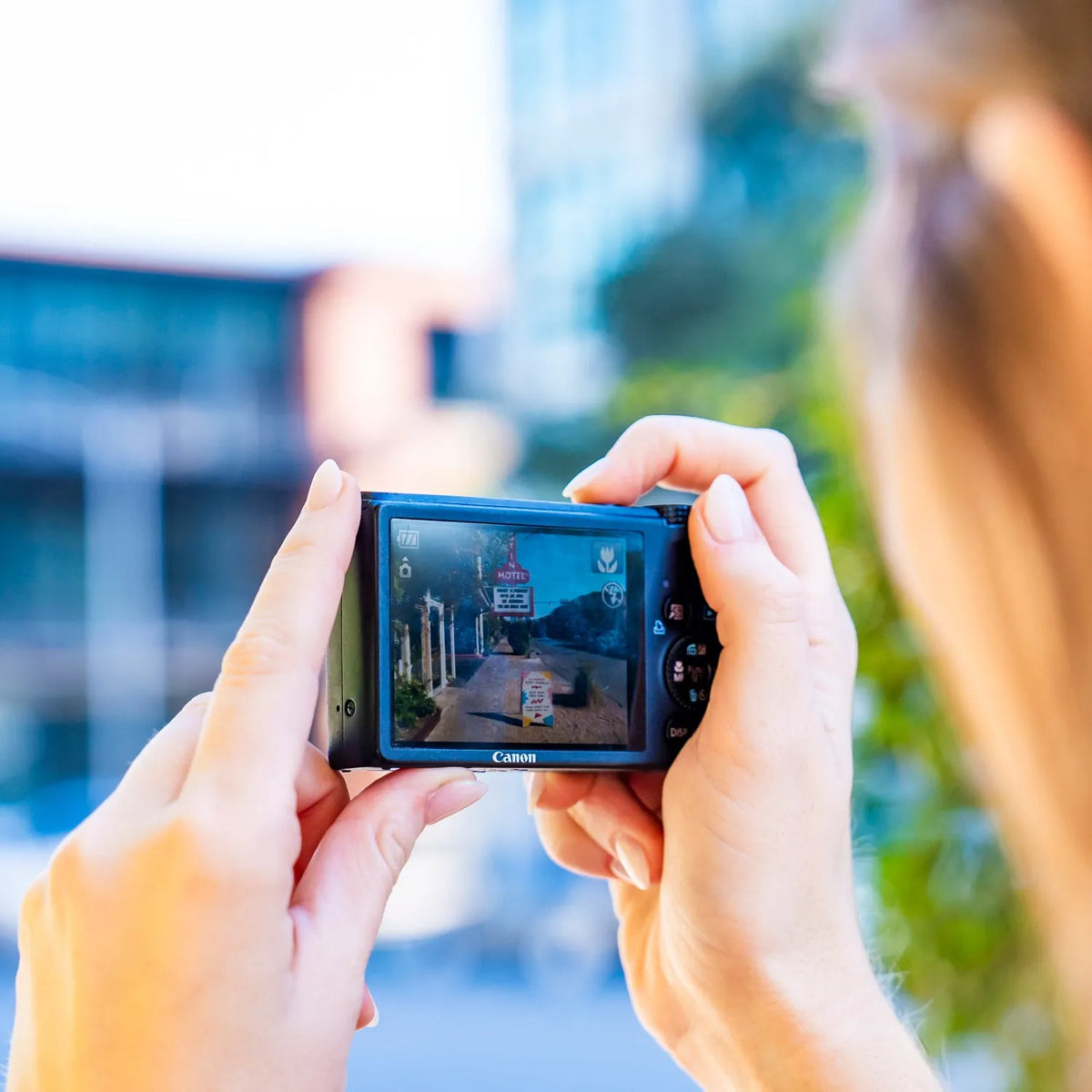 Canon PowerShot S95 LCD screen displaying a street scene while held outdoors