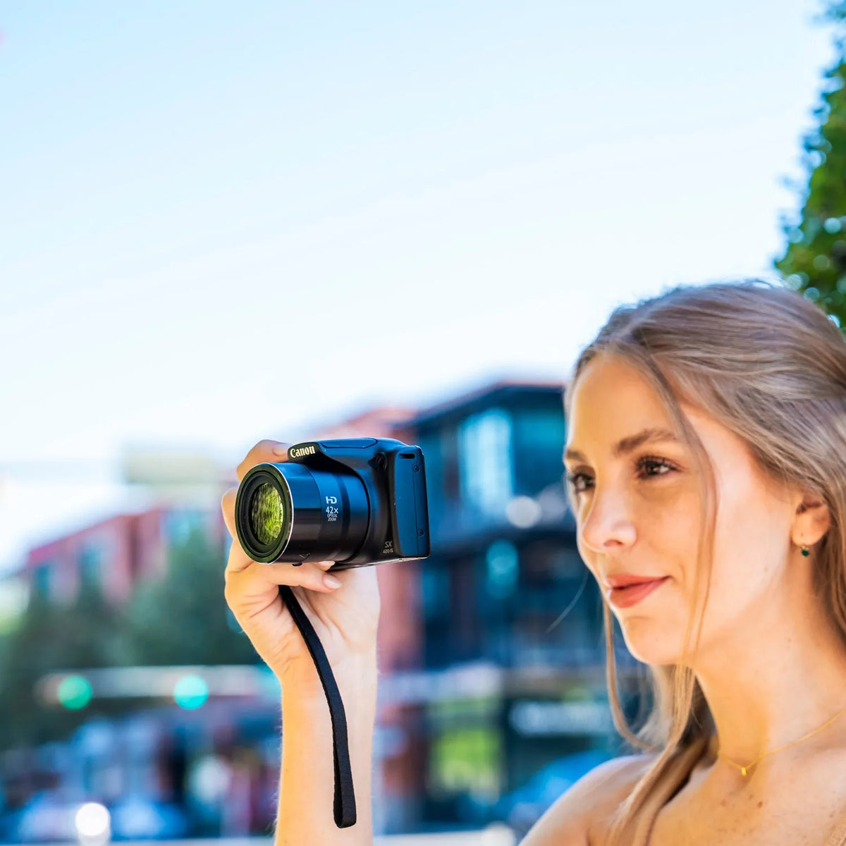 Woman composing a photo outdoors with the zoom lens extended on a Canon PowerShot SX420 IS
