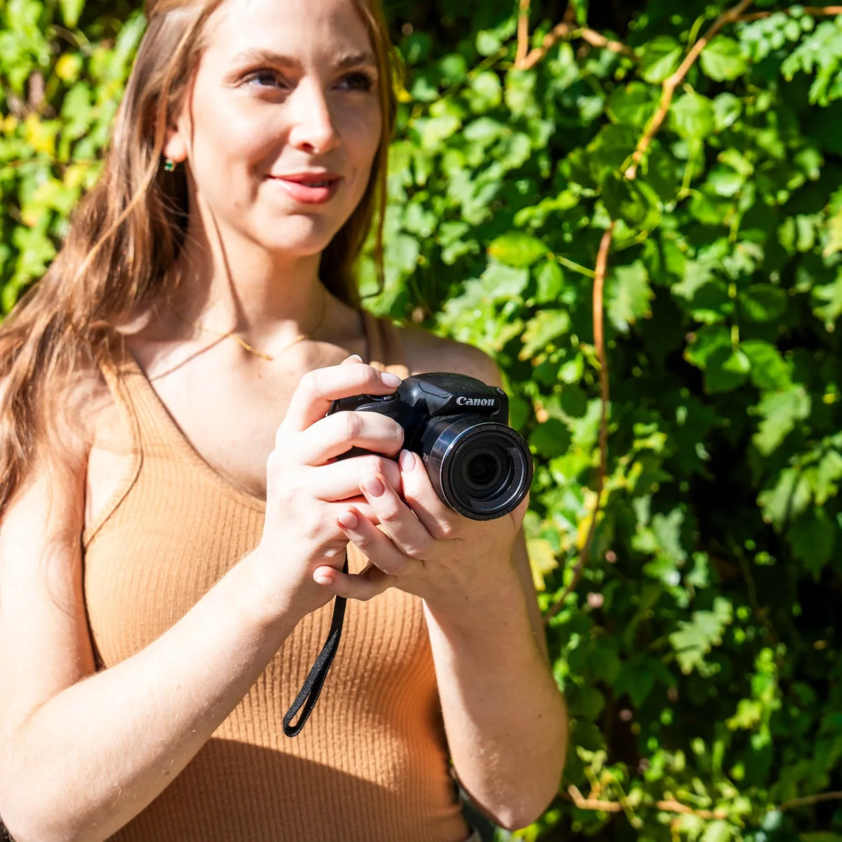Woman holding a Canon PowerShot SX420 IS bridge camera outdoors