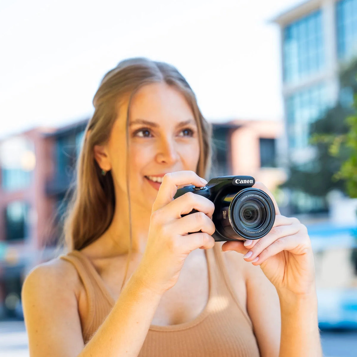 Woman holding a Canon PowerShot SX530 HS bridge camera outdoors
