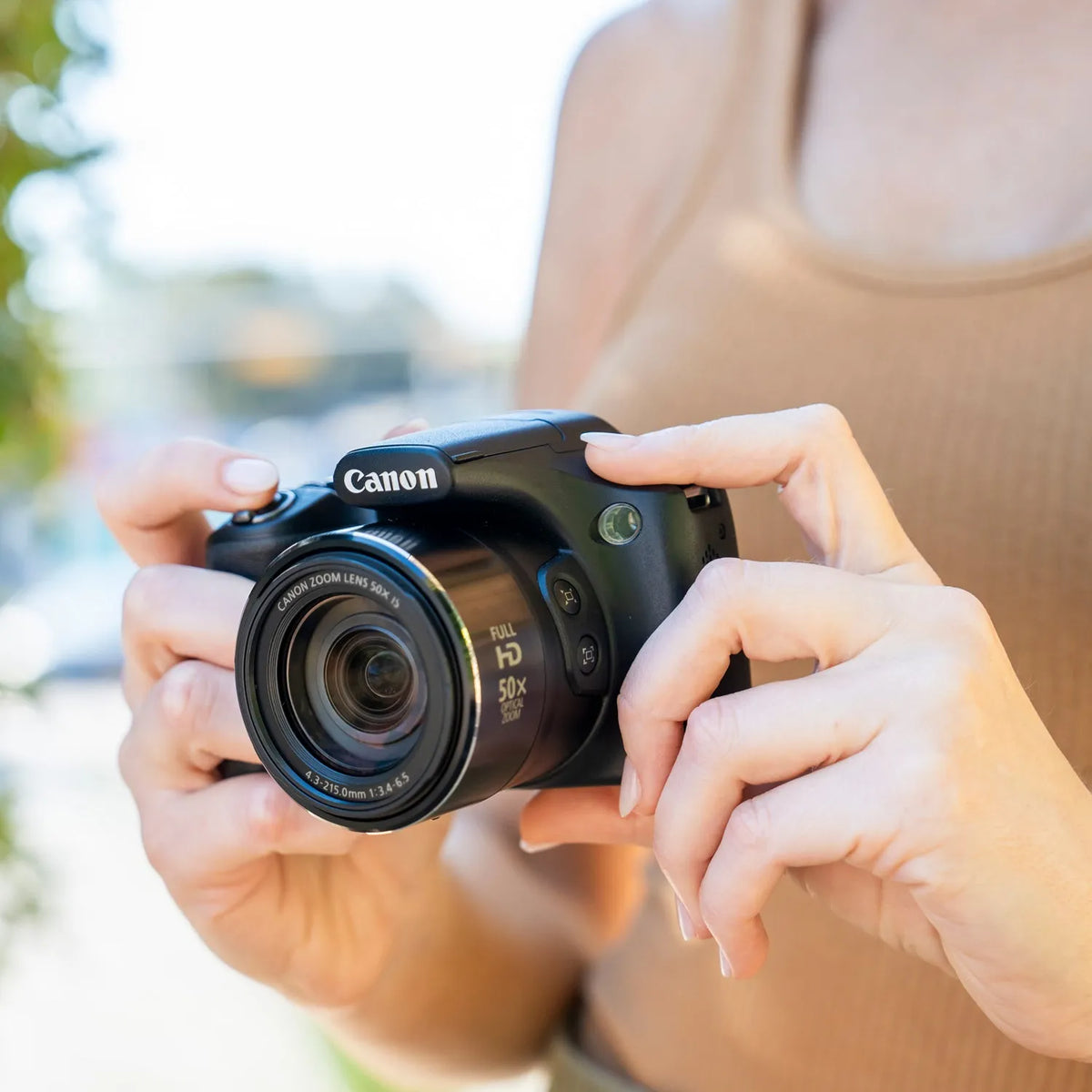 Close-up of a woman holding the Canon PowerShot SX530 HS with its 50x zoom lens