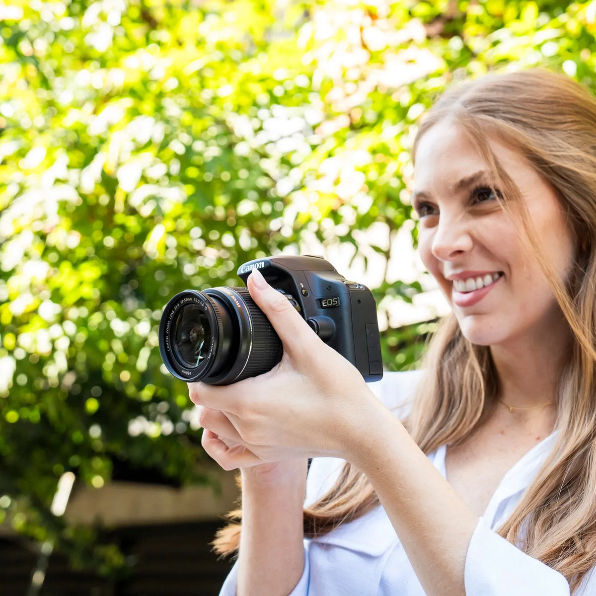 Woman holding a Canon Rebel T1i DSLR camera outdoors