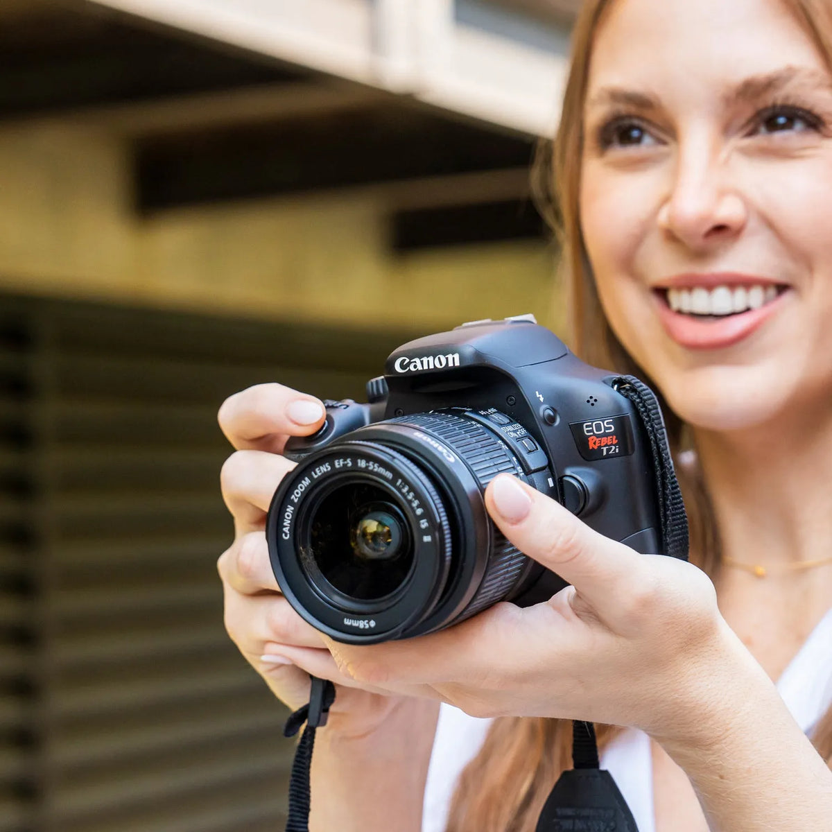Woman holding a Canon Rebel T2i DSLR camera outdoors