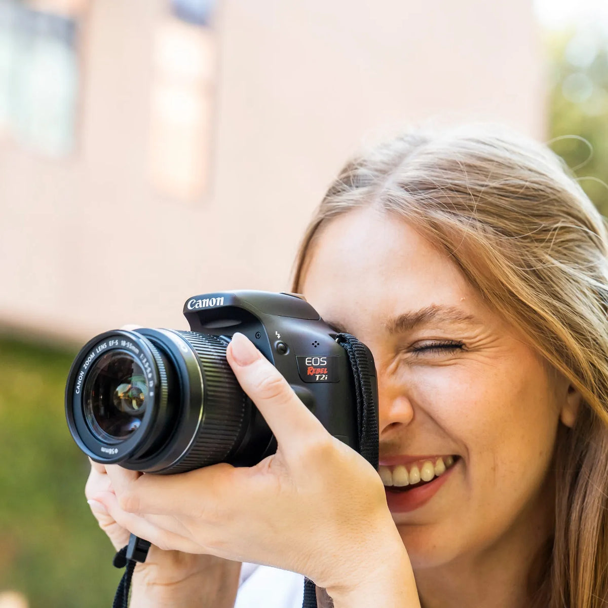 Woman taking a photograph outdoors with a Canon Rebel T2i DSLR camera