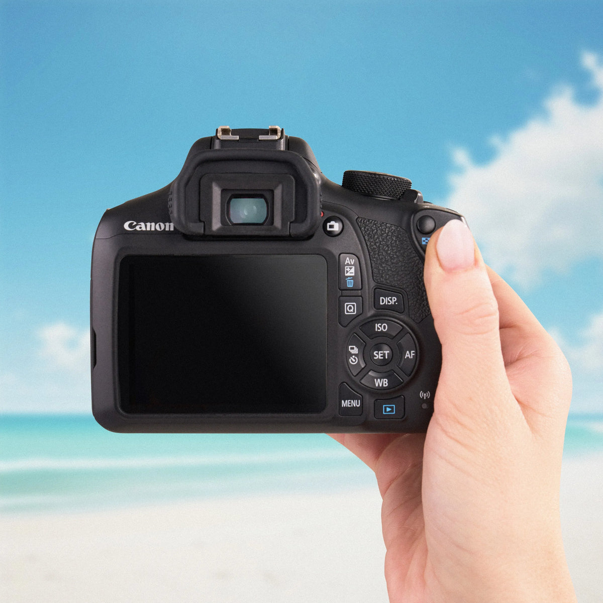 Canon Rebel T6 DSLR Camera held in a hand with a beach background