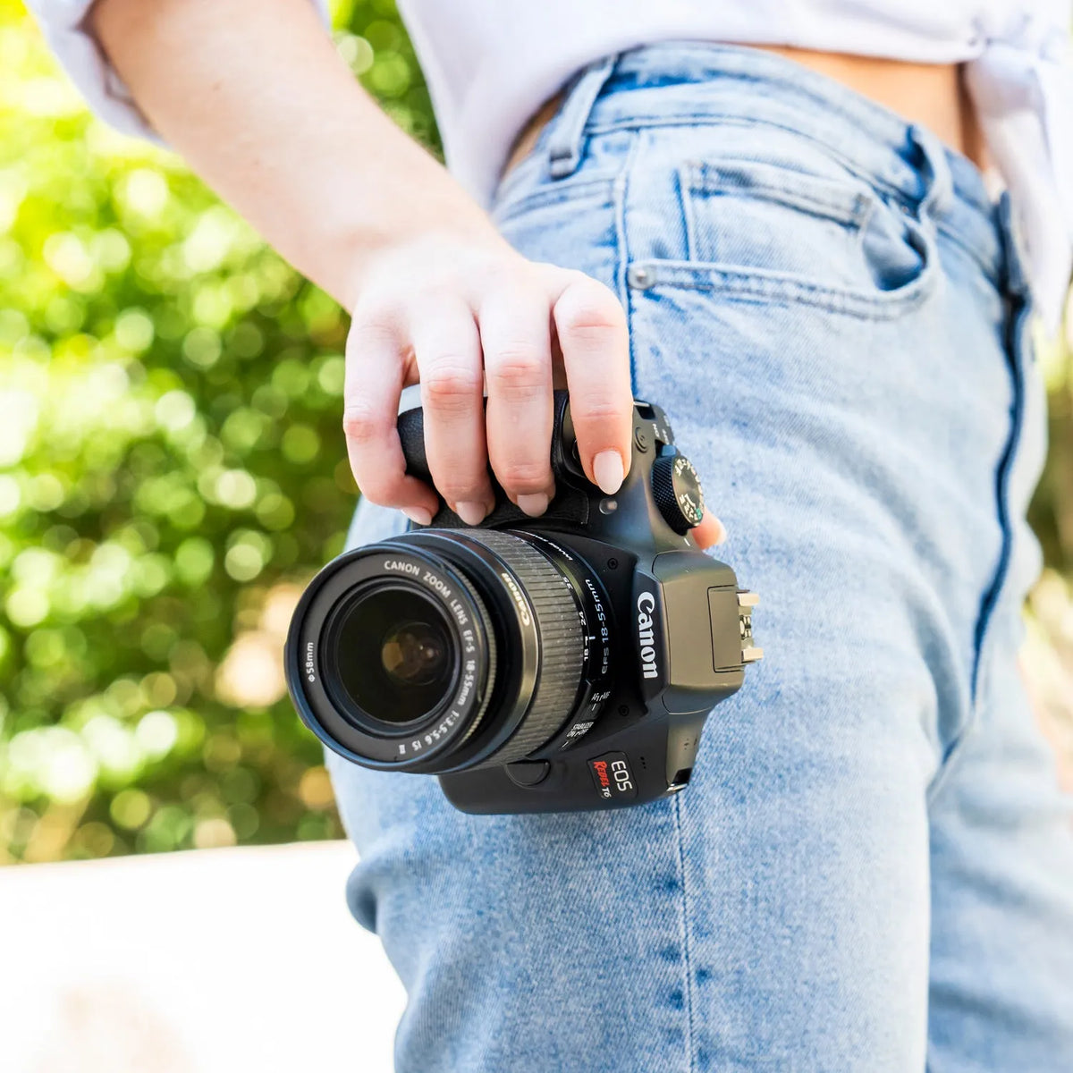 Person holding a Canon camera with a blurred green background