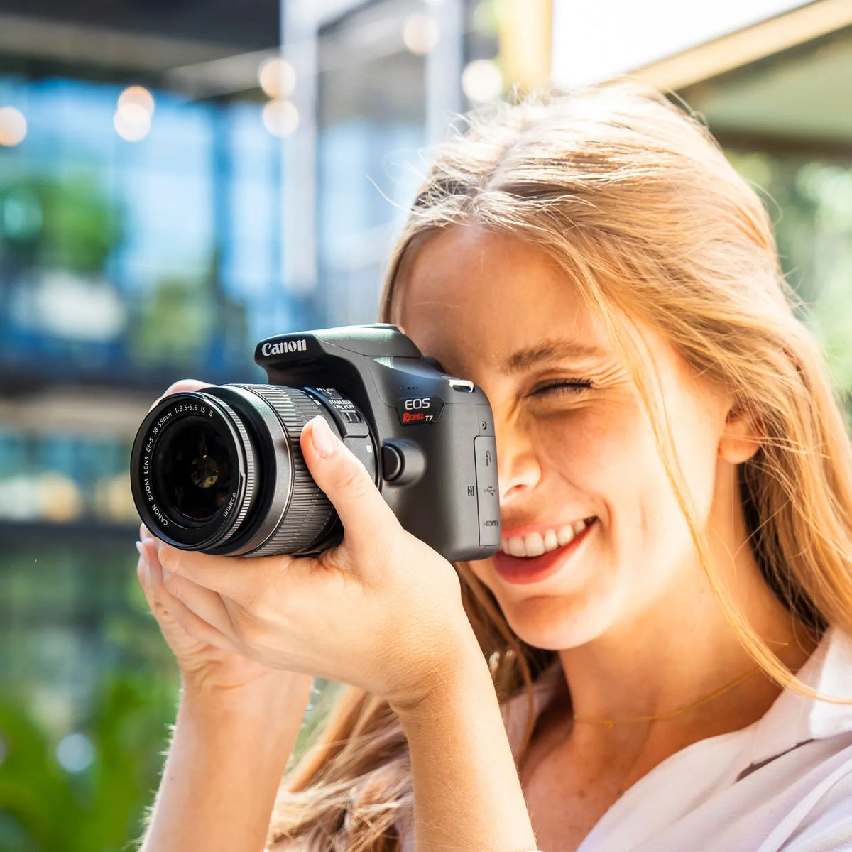 Woman taking a photograph outdoors with a Canon Rebel T7 DSLR camera