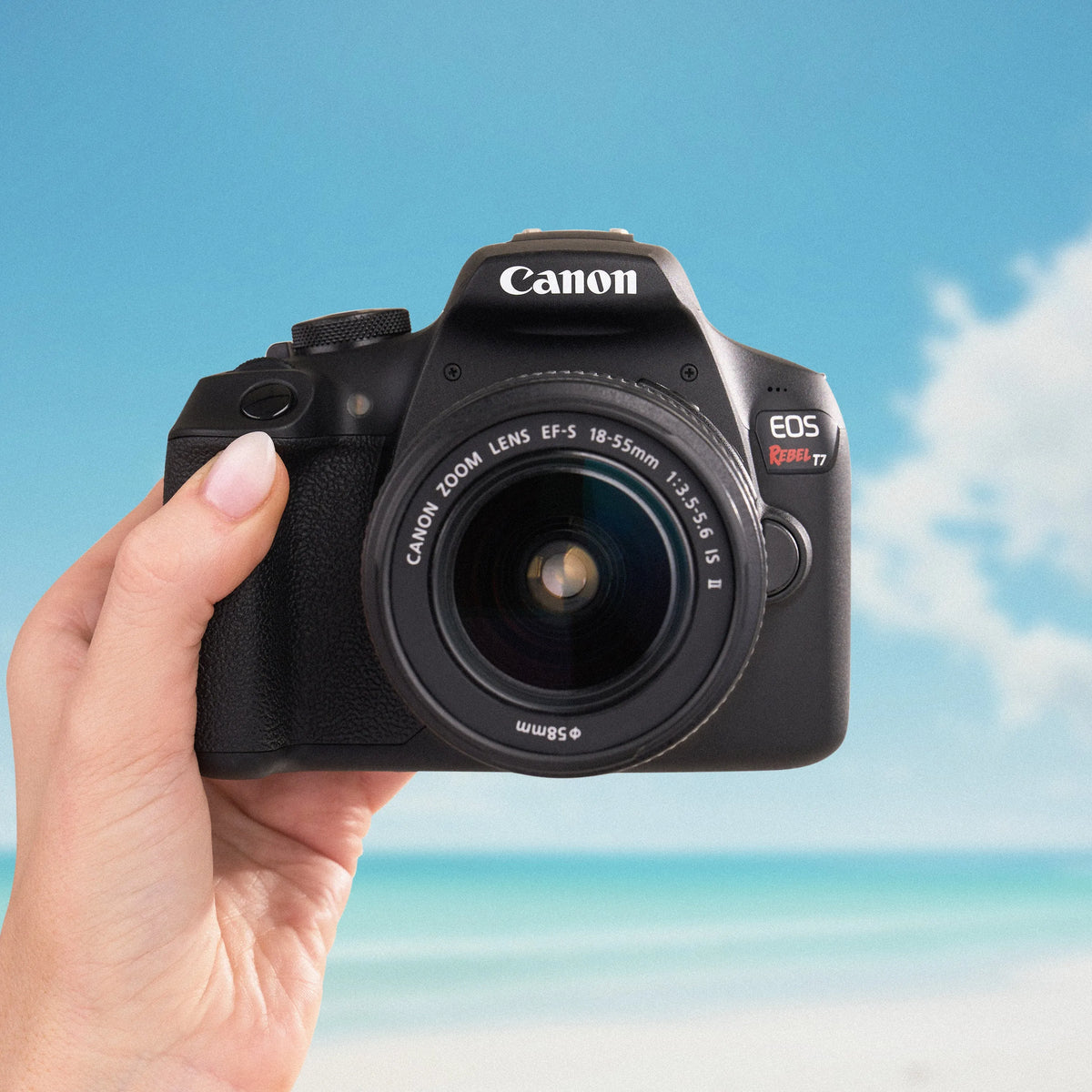 Canon Rebel T7 DSLR camera with an 18–55mm lens held against a beach backdrop