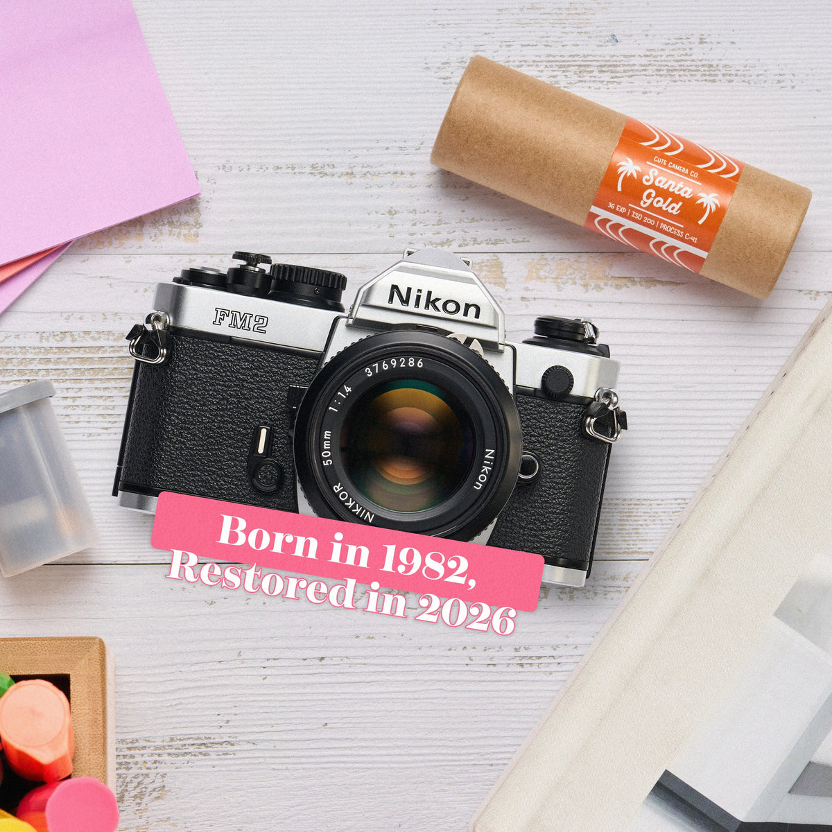 Nikon FM2 Film Camera on a white surface with text indicating its birth year and restoration year.