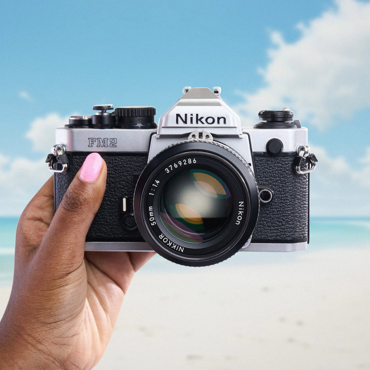 Nikon FM2 Film Camera held by a hand with a beach background