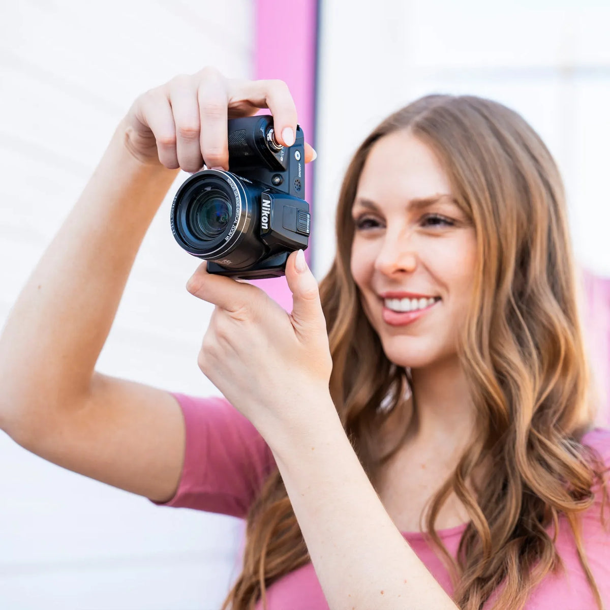 Woman smiling while framing a photograph with a Nikon COOLPIX L110