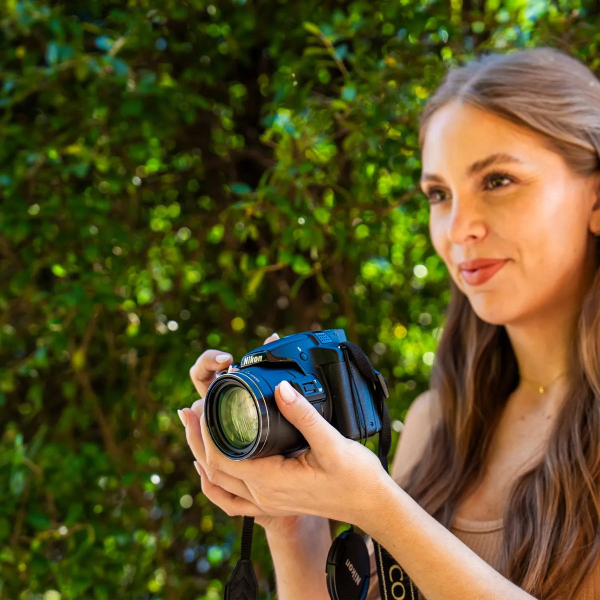 Woman preparing to take a photograph outdoors with a Nikon COOLPIX P510
