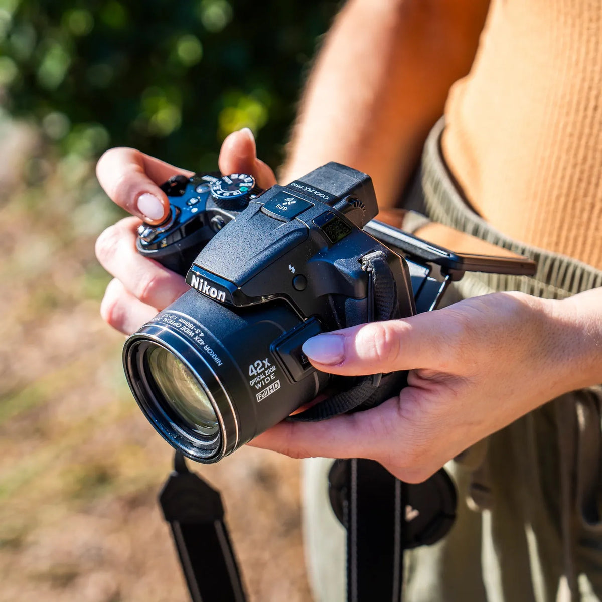 Close-up of a woman holding a Nikon COOLPIX P510 and its 42x optical zoom lens outdoors