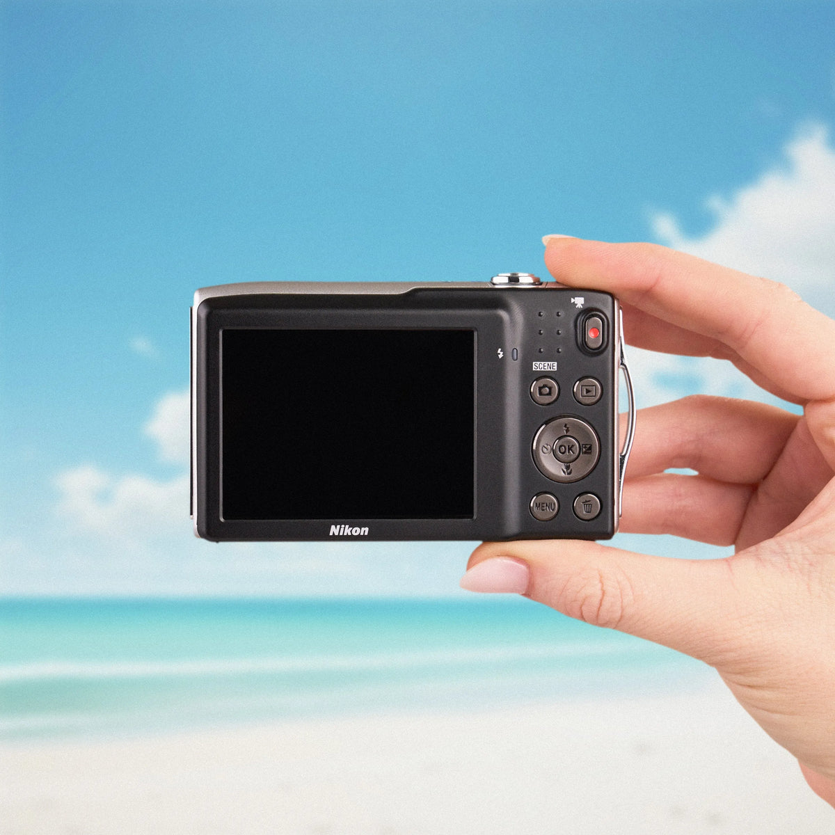 Back view of a silver Nikon COOLPIX S3300 showing its LCD screen and controls at the beach