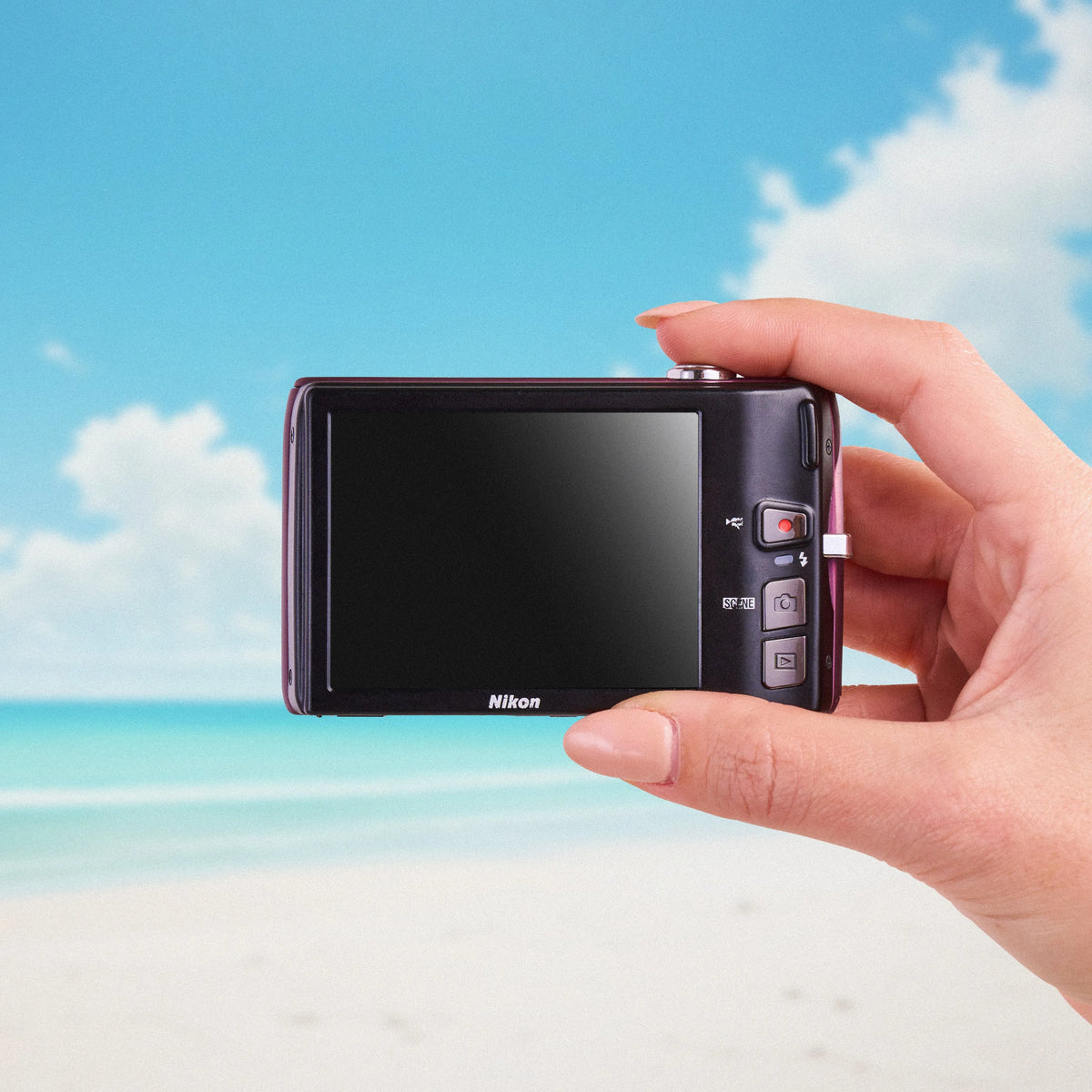 Back view of a Nikon Coolpix S4100 showing its touchscreen display against a beach background