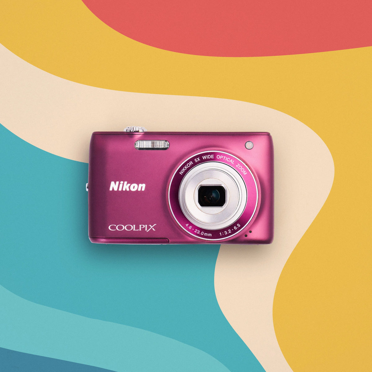 Purple Nikon Coolpix S4100 retro digital camera on a colorful wavy background