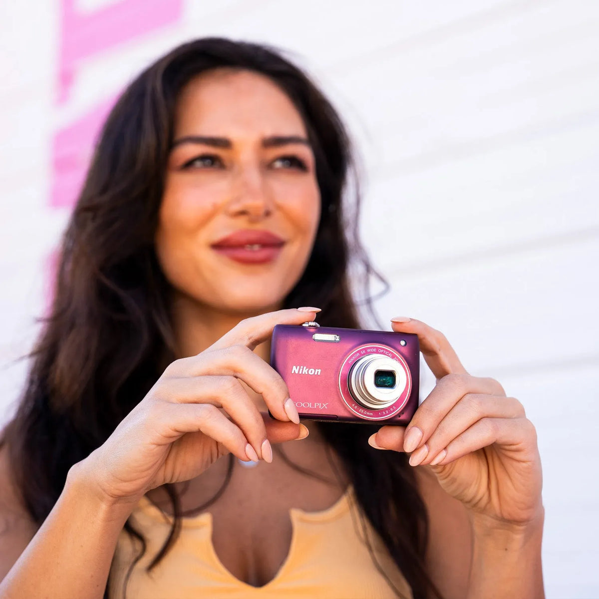 Woman holding a purple Nikon Coolpix S4100 point-and-shoot digital camera outdoors