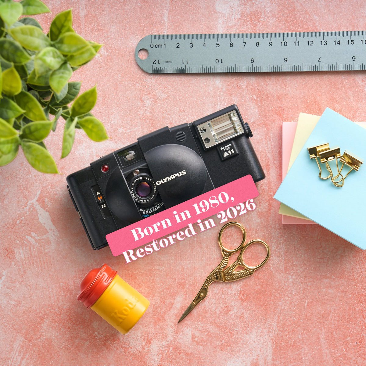 Vintage Olympus XA 2 | 35mm Point and Shoot Film Camera on a pink surface with stationery items and text overlay