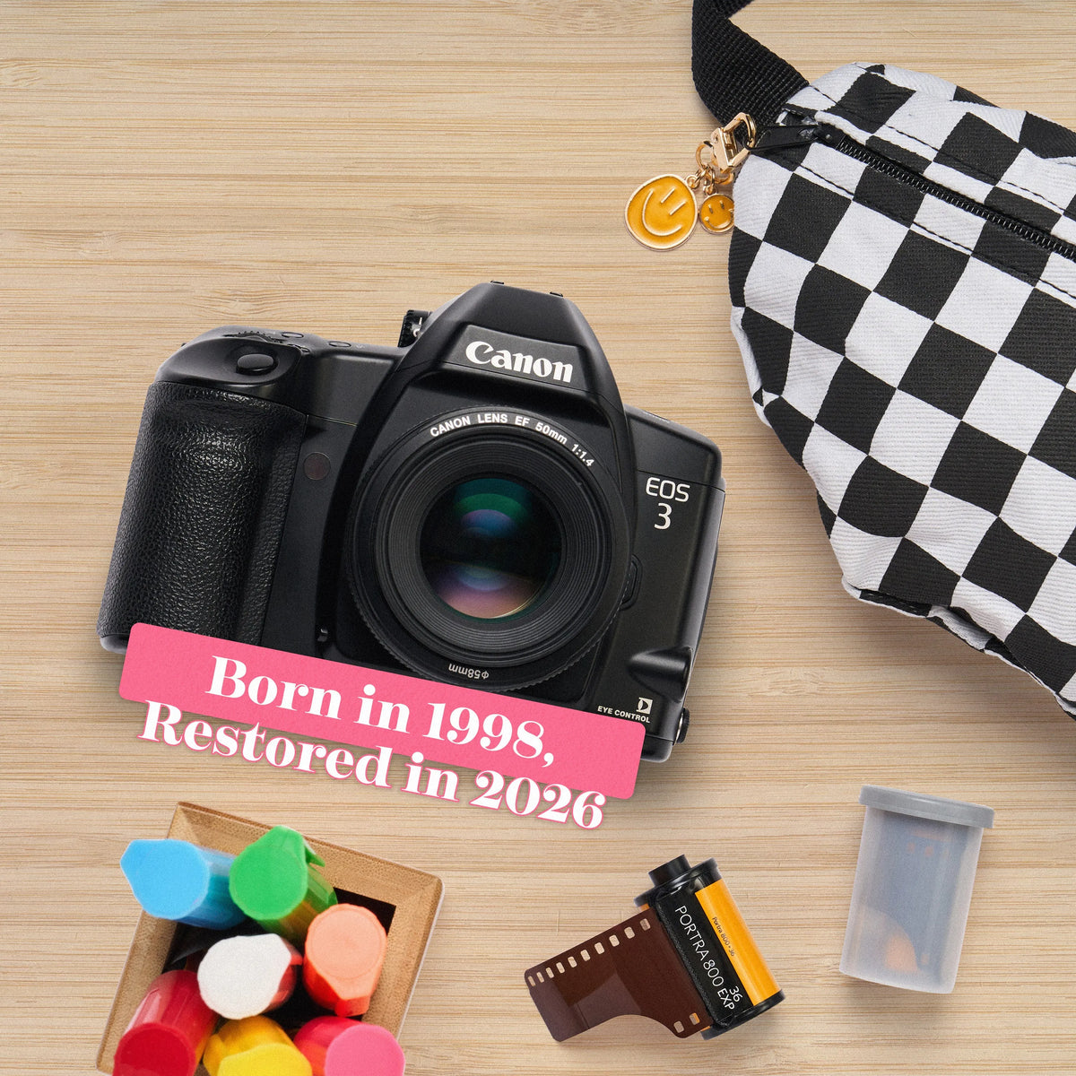 Canon EOS 3 Film Camera with colorful markers and a checkered bag on a wooden surface