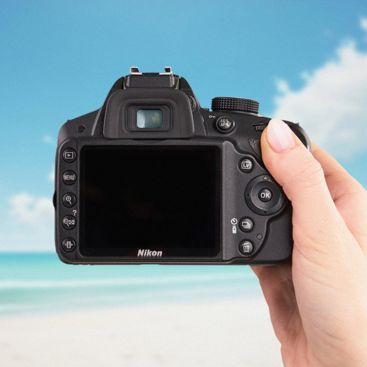 Nikon D3200 DSLR Camera held in a hand with a beach background