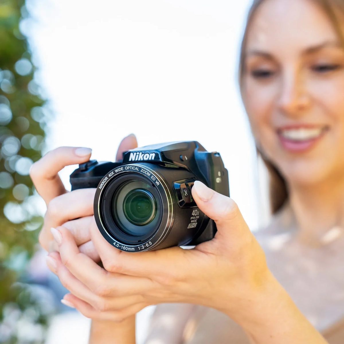 Woman holding a Nikon COOLPIX B500 bridge camera outdoors