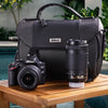Nikon D3200 DSLR Camera with lens and bag on a wooden table outdoors