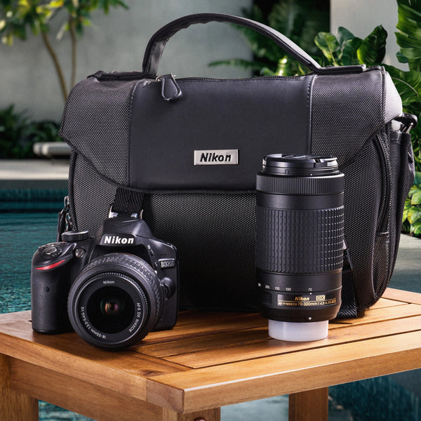 Nikon D3200 DSLR Camera with lens and bag on a wooden table outdoors