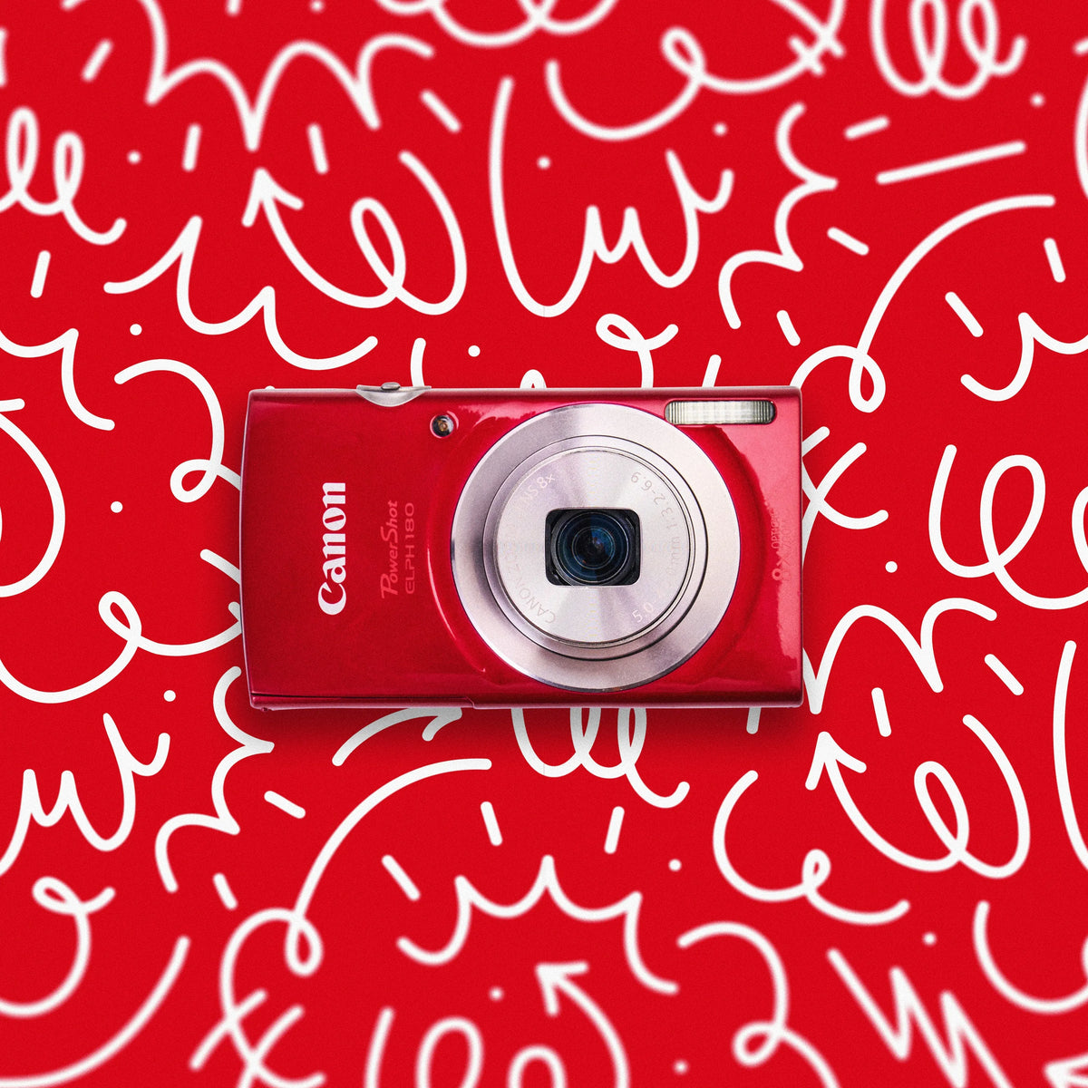 Front view of a red Canon PowerShot ELPH 180 retro digital camera on a red doodle background