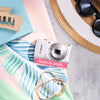 Restored Canon PowerShot ELPH 180 styled with summer accessories and text reading “Born in 2016, Restored in 2026”