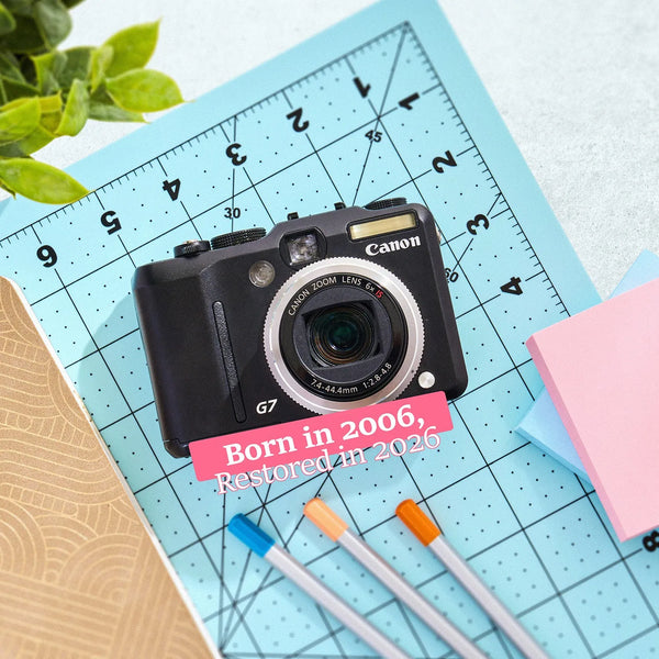 Restored Canon PowerShot G7 styled with stationery and text reading “Born in 2006, Restored in 2026”