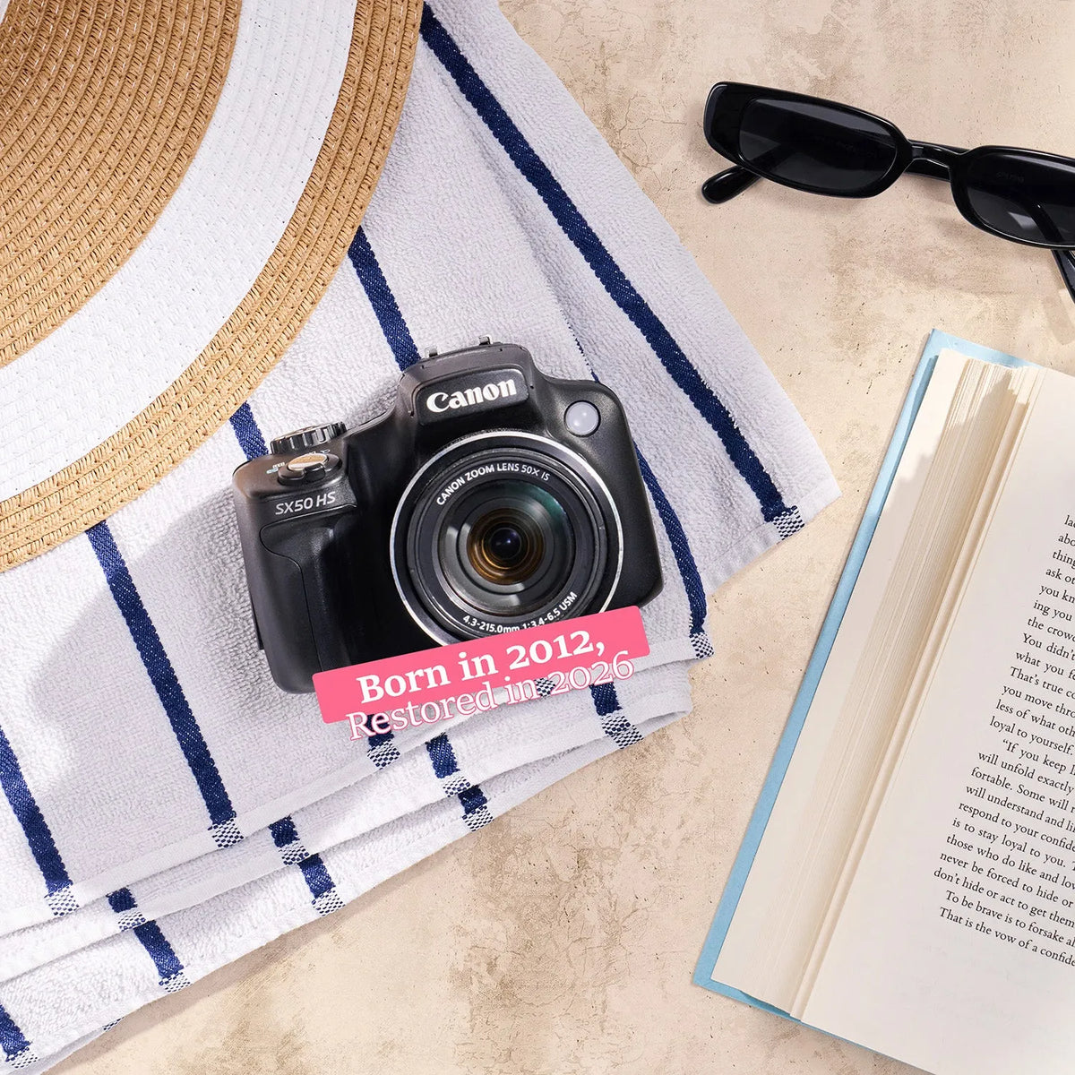 Restored Canon PowerShot SX50 HS styled with beach accessories and text reading “Born in 2012, Restored in 2026”