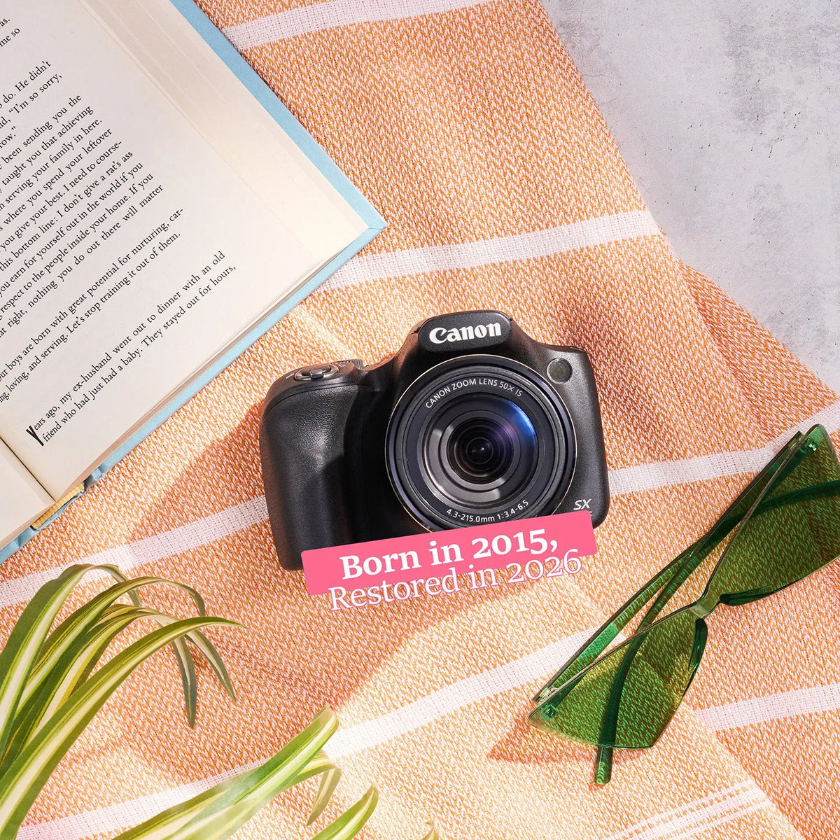 Restored Canon PowerShot SX530 HS styled with a book and sunglasses, labeled Born in 2015, Restored in 2026