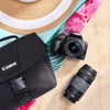 Canon Rebel T2i dual-lens kit arranged with a camera bag, sun hat and colorful accessories