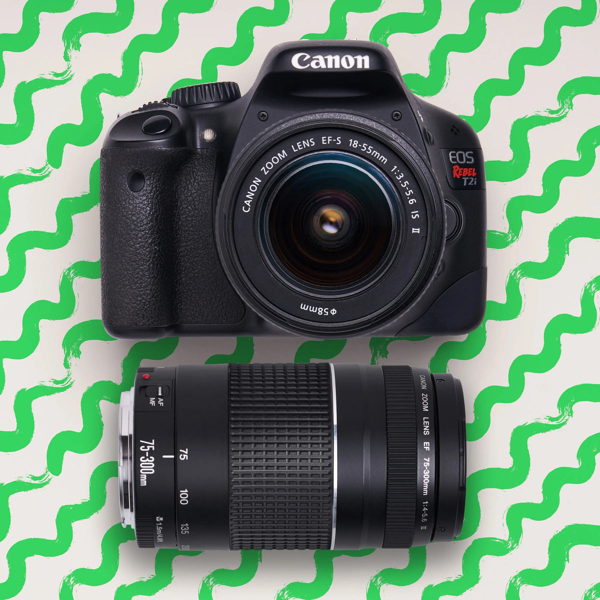 Canon Rebel T2i DSLR camera with 18–55mm and 75–300mm lenses on a green patterned background