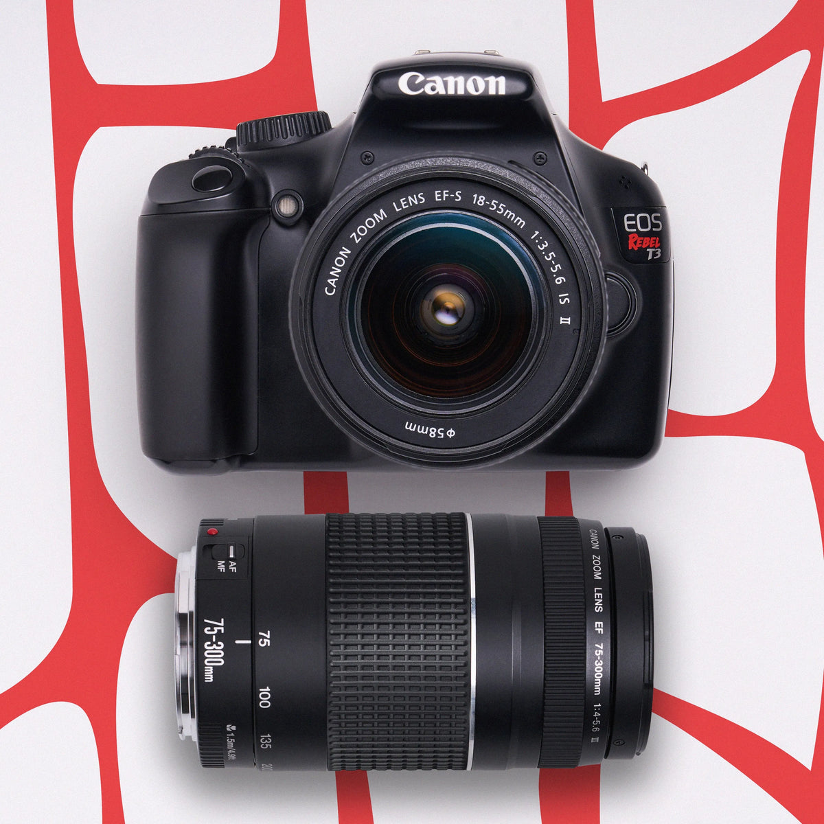 Canon Rebel T3 DSLR camera with 18–55mm and 75–300mm lenses on a red patterned background
