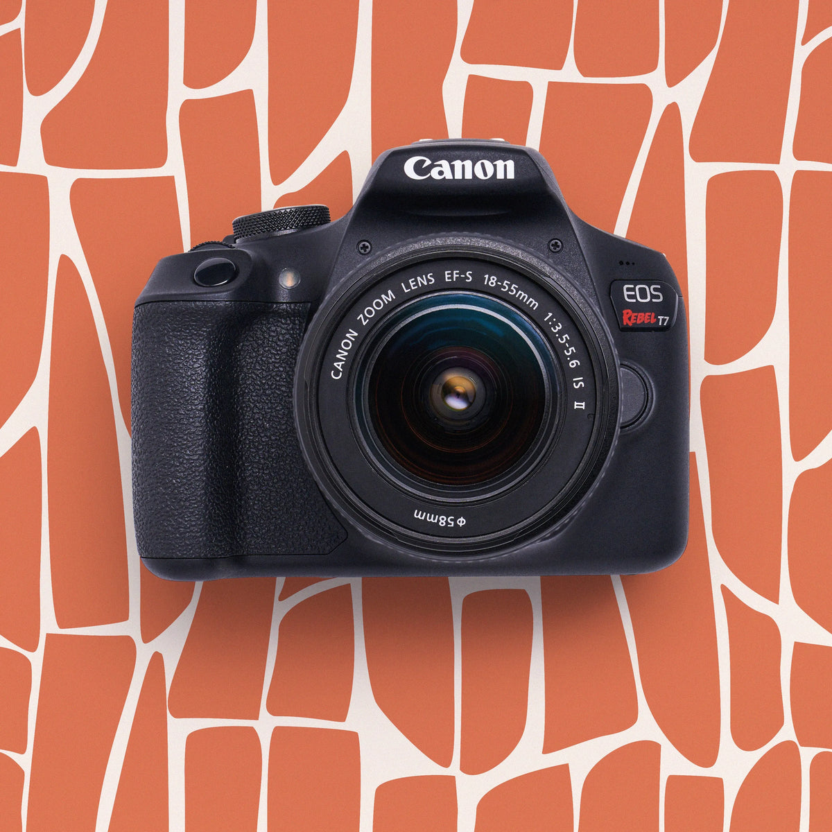 Front view of a restored Canon Rebel T7 DSLR camera with an 18–55mm lens on an orange patterned background